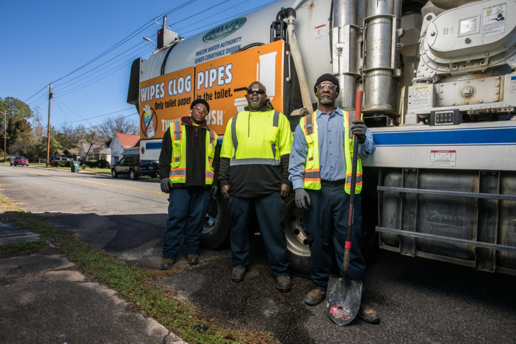 Three guys beside a utility truck