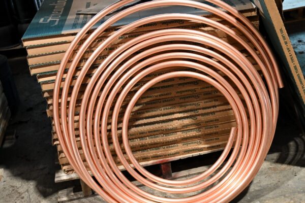 A coil of copper tubing resting against a stack of cardboard boxes labeled Streamline copper plumbing tube.