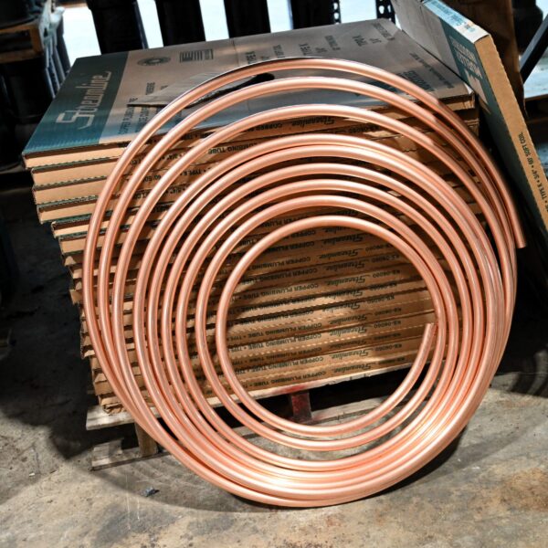 A coil of copper tubing resting against a stack of cardboard boxes labeled Streamline copper plumbing tube.